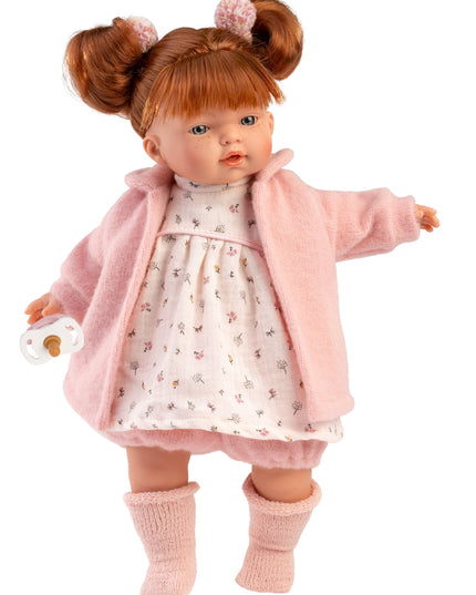 Doll wearing a pink coat and dress with a white background