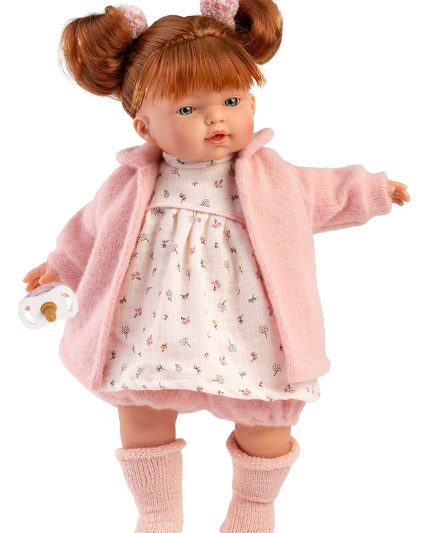Doll wearing a pink coat and dress with a white background