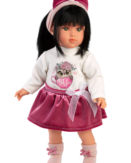 Doll wearing a white sweater with an owl design and a pink skirt on a white background