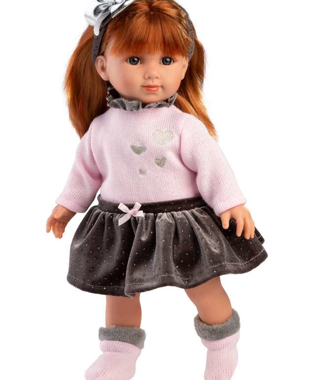 Doll with long brown hair wearing a pink sweater and gray skirt on a white background