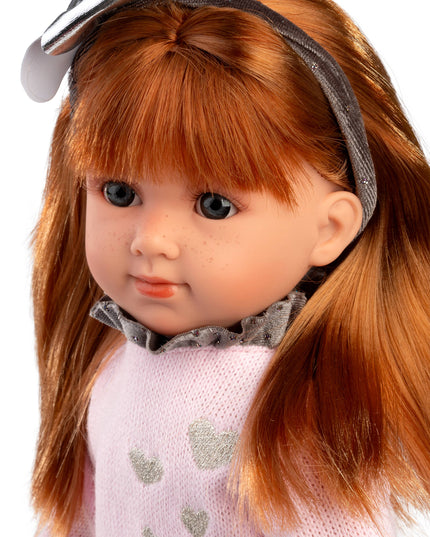 Close-up of a doll with red hair and a pink outfit on a white background