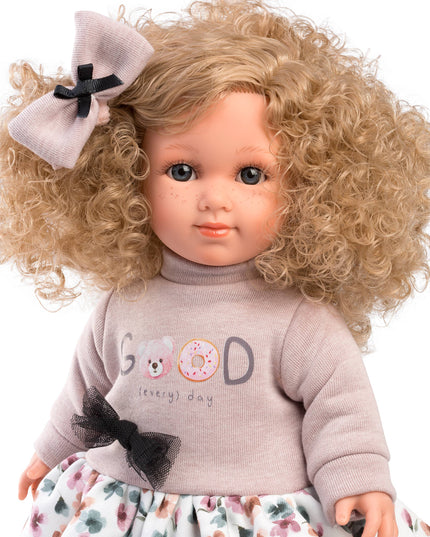 Doll with blonde curly hair, floral dress, and 'Good Day' sweater on a white background