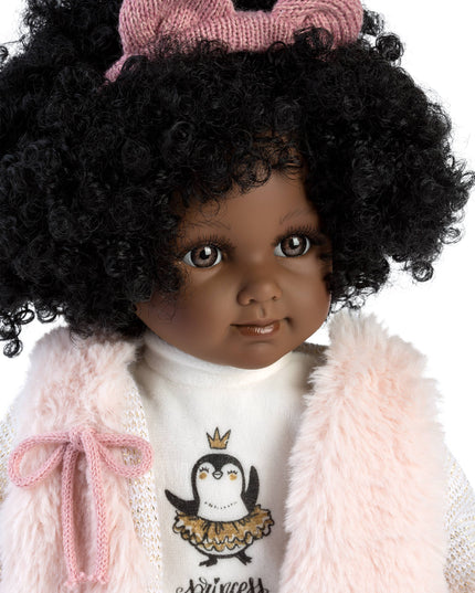 Doll with curly hair wearing a pink outfit with a bow, white shirt with penguin design, and pink coat.
