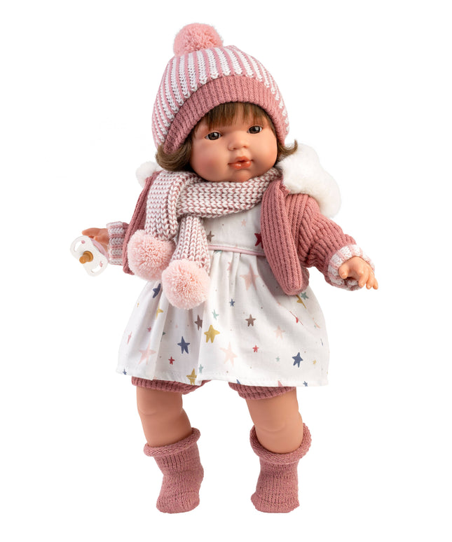 Doll wearing a pink knitted hat, scarf, and socks on a white background
