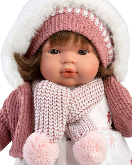 Doll wearing a pink knitted hat, scarf, and coat with white fur trim on a white background