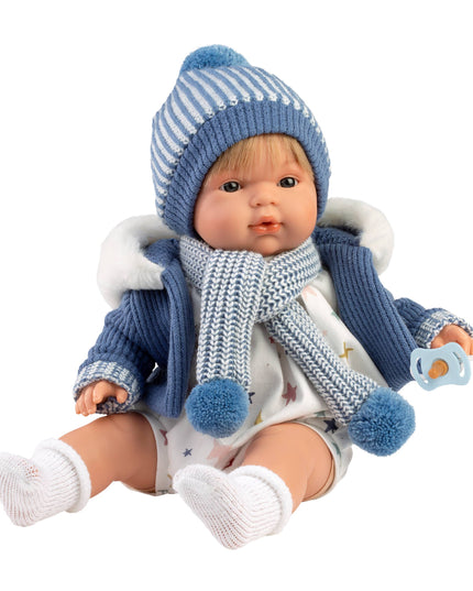 Baby doll wearing a blue winter outfit with a striped hat and scarf on a white background