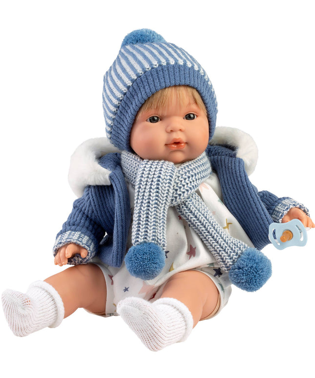 Baby doll wearing a blue winter outfit with a striped hat and scarf on a white background