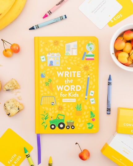 Yellow book titled 'Write the Word for Kids' on a pink surface with educational materials and snacks.