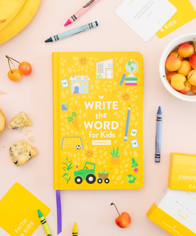 Yellow book titled 'Write the Word for Kids' on a pink surface with educational materials and snacks.