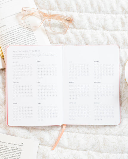 Notebook, glasses, and a cup on a textured white surface