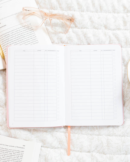 Open notebook with grid pages on a marble surface with books and a teacup.