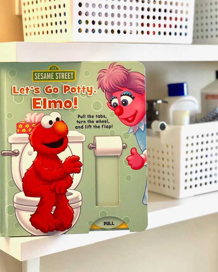 Sesame Street book titled 'Let's Go Potty, Elmo!' on a shelf.