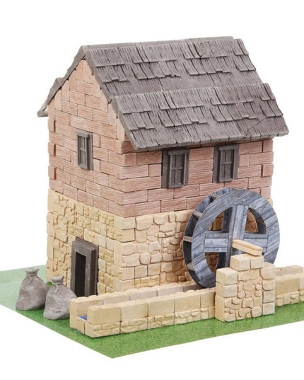 Model of a stone building with a water wheel on a white background