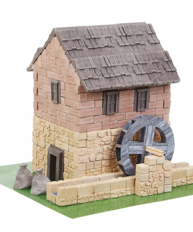 Model of a stone building with a water wheel on a white background