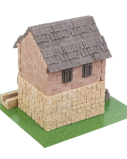 Model of a small house with a thatched roof on a green base
