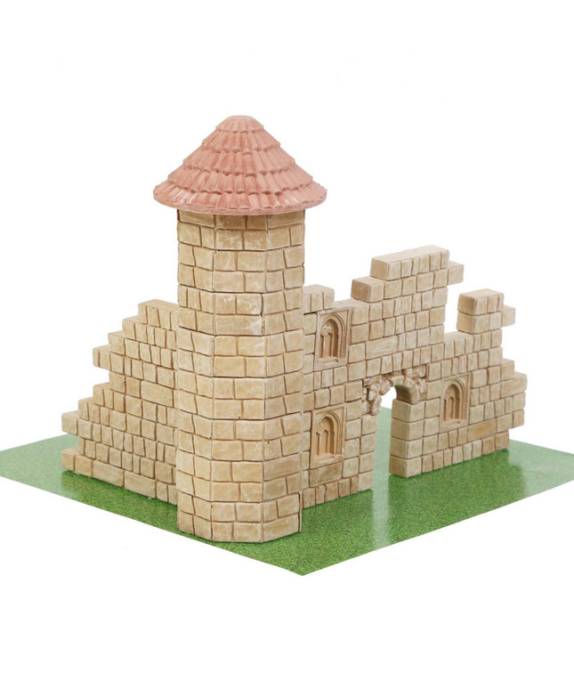 Model of a castle made from interlocking bricks on a green base with a white background