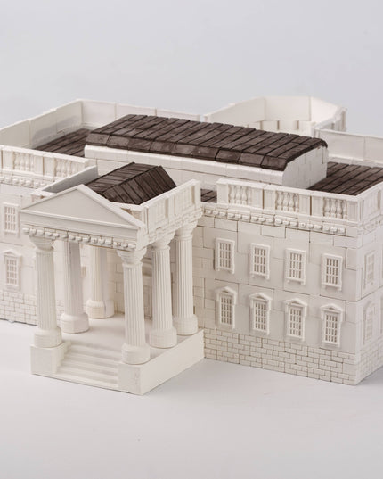 Model of a building with a white facade and dark roof on a light gray background