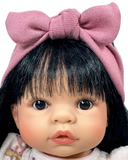 Doll with black hair and a large pink bow on a white background