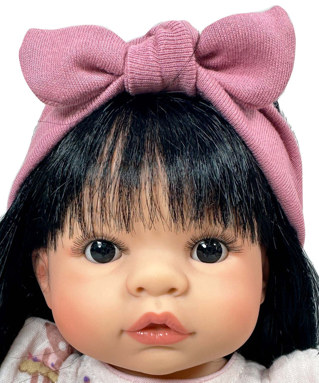 Doll with black hair and a large pink bow on a white background