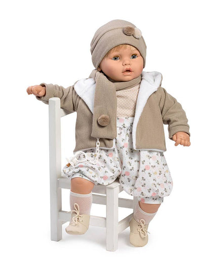 Baby doll wearing a beige outfit with a jacket, hat, and floral dress on a white background