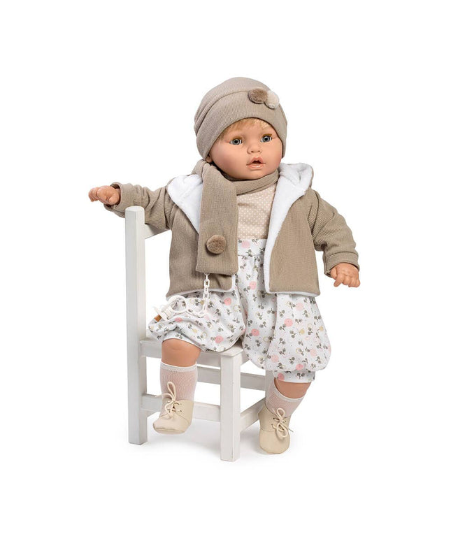 Baby doll wearing a beige outfit with a jacket, hat, and floral dress on a white background