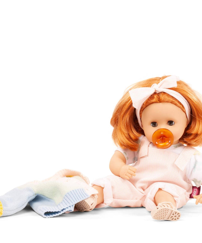 Baby doll with red hair and a pacifier sitting on a white background