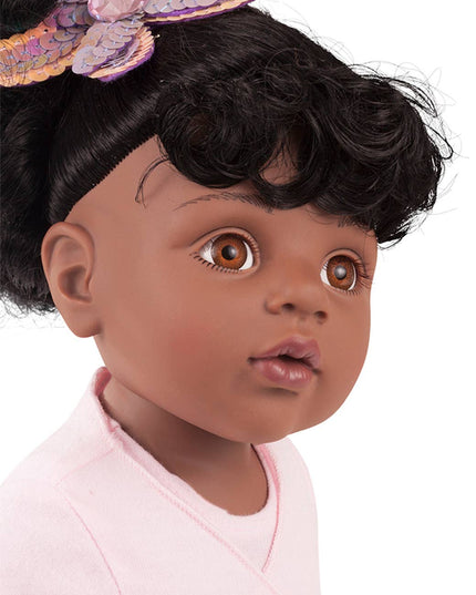 Close-up of a doll with dark skin, black hair, and a butterfly headband on a white background.