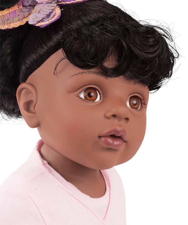 Close-up of a doll with dark skin, black hair, and a butterfly headband on a white background.