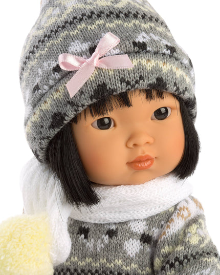 Doll wearing a gray knitted hat with a pink bow and matching outfit on a white background