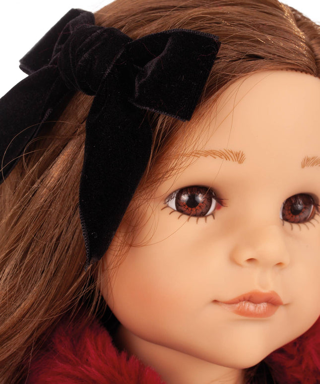 Close-up of a doll with brown hair and a black bow, wearing a red garment.