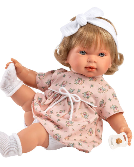 Baby doll with blonde hair, floral dress, and pacifier on a white background