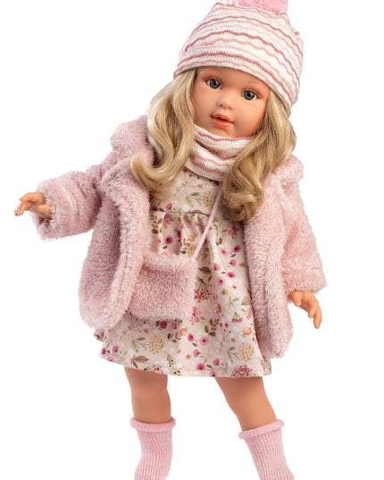 Doll wearing a pink outfit with a coat, dress, hat, and bag on a white background