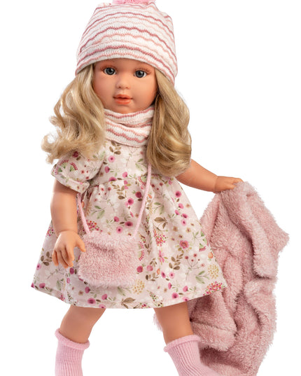 Doll wearing a floral dress, pink hat with pom-pom, and pink scarf on a white background