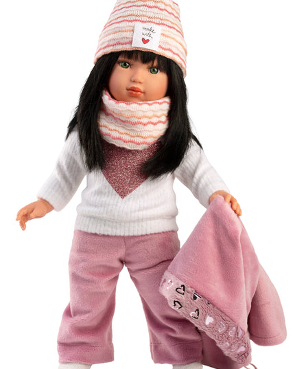 Doll wearing a white sweater, pink pants, and striped hat with a scarf on a white background