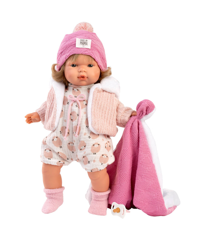 Doll in pink outfit with hat and blanket on a white background