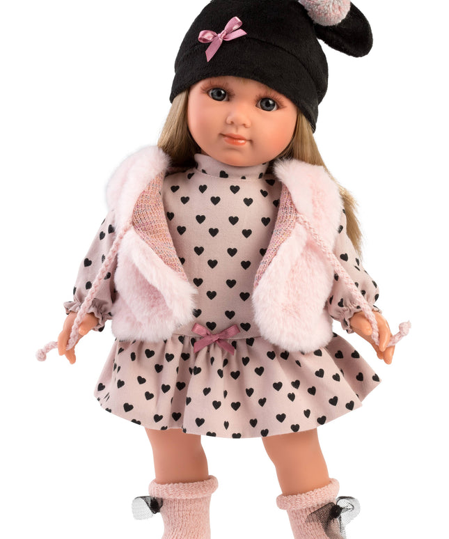 Doll wearing a black hat with a pink bow, heart-patterned dress, and pink coat on a white background