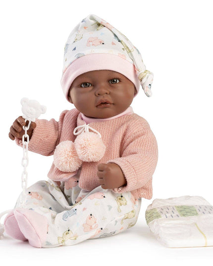 Baby doll in pink outfit with pacifier and blanket on white background