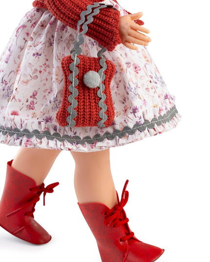 Doll wearing a floral dress with a red hood and boots on a white background