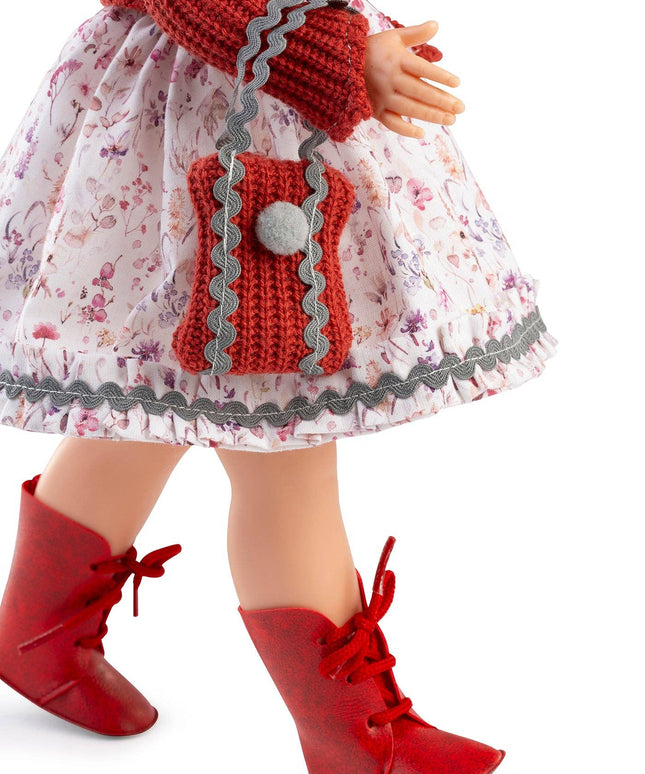 Doll wearing a floral dress with a red hood and boots on a white background