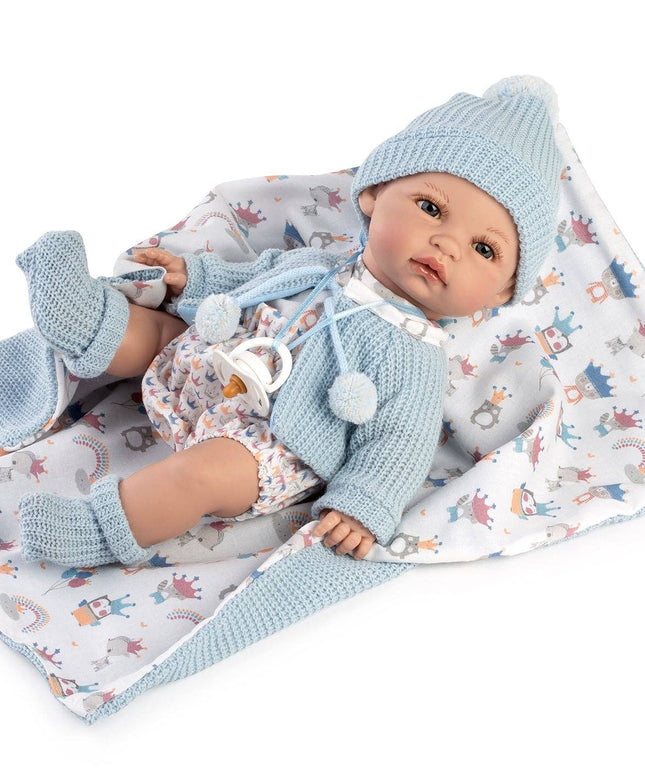 Baby doll in blue outfit with matching hat and socks on a patterned blanket