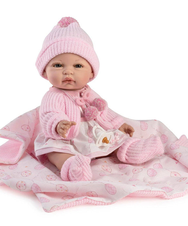 Baby doll in pink outfit with matching hat and blanket on a white background