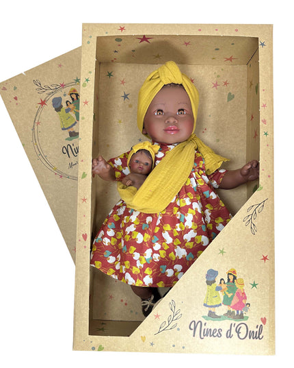 Doll in a floral dress with a yellow headscarf in a decorative box, featuring 'Nines d'Onil' branding.