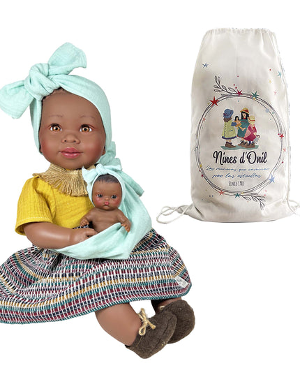 Doll holding a smaller doll with a 'Nines d'Oril' bag in the background