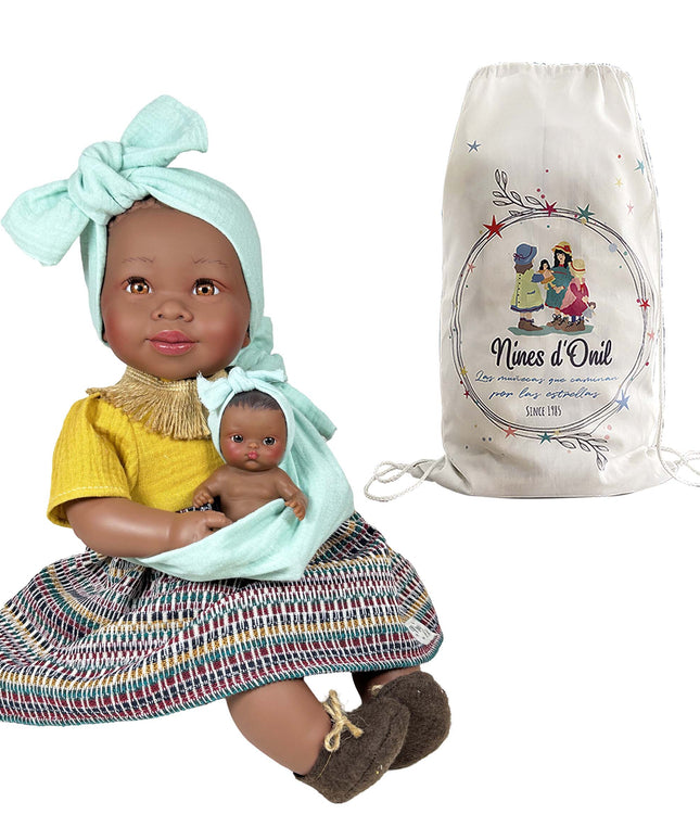 Doll holding a smaller doll with a 'Nines d'Oril' bag in the background