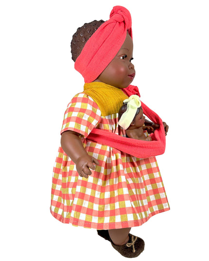 Doll wearing a red checkered dress with a pink headscarf on a white background