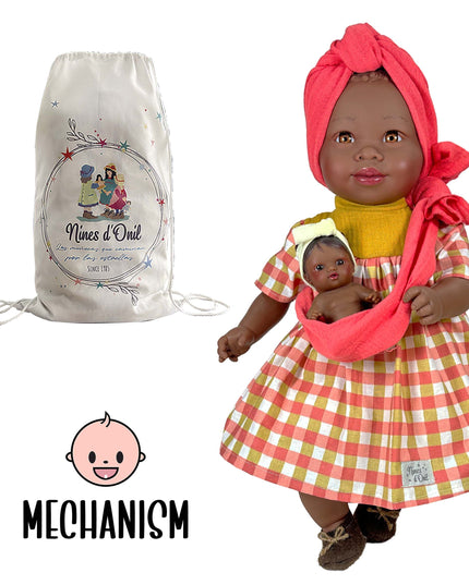 Doll in a checkered dress with a baby in a sling, next to a branded bag, on a white background.