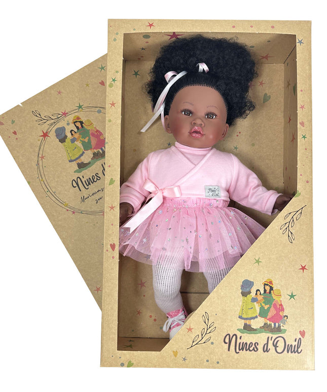 Doll in a pink outfit with a white bow in a cardboard box, branded 'Nines d'Oril'.