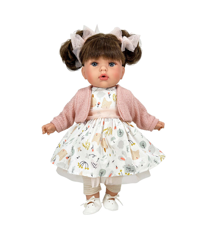 Doll wearing a pink cardigan and patterned dress on a white background