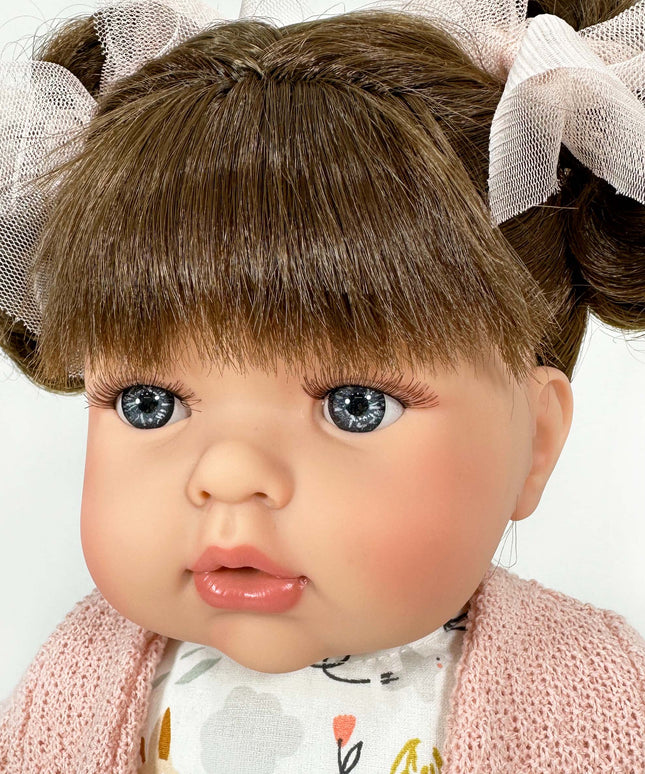 Close-up of a doll with braided hair and a pink sweater on a white background