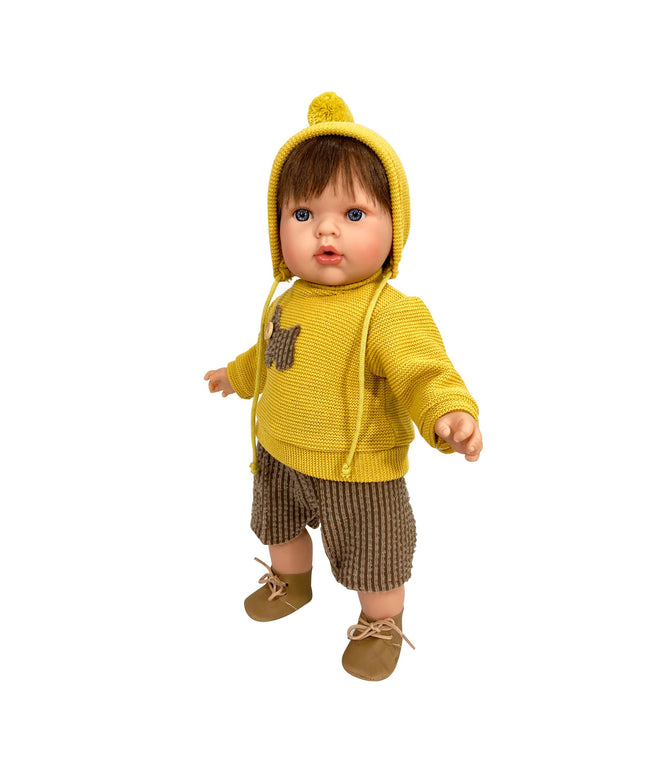 Baby doll wearing a yellow knitted outfit with a hood on a white background